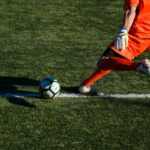 man kicking soccer ball on field